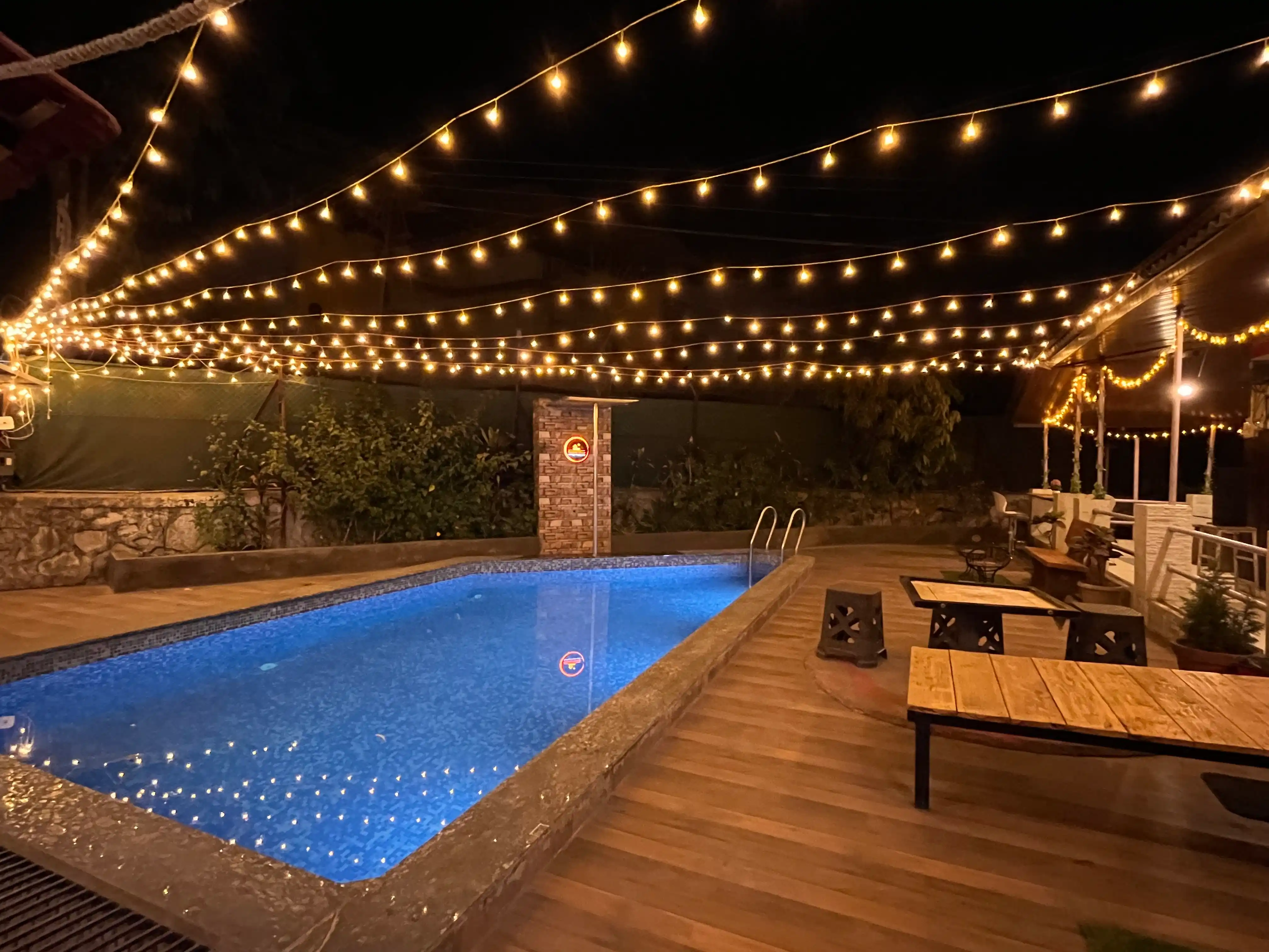 Govind Villa poolside view at night, illuminated by warm ambient lighting, highlighting the luxurious 3BHK penthouse and serene surroundings.